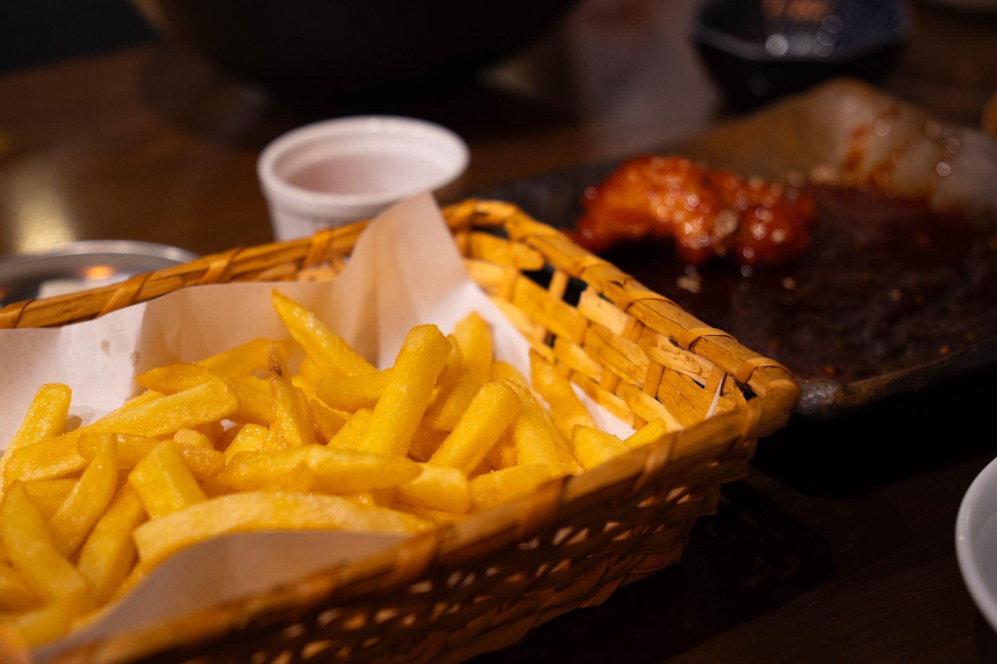 Fries on the table with yangnyeom chicken in the background at Chijimi